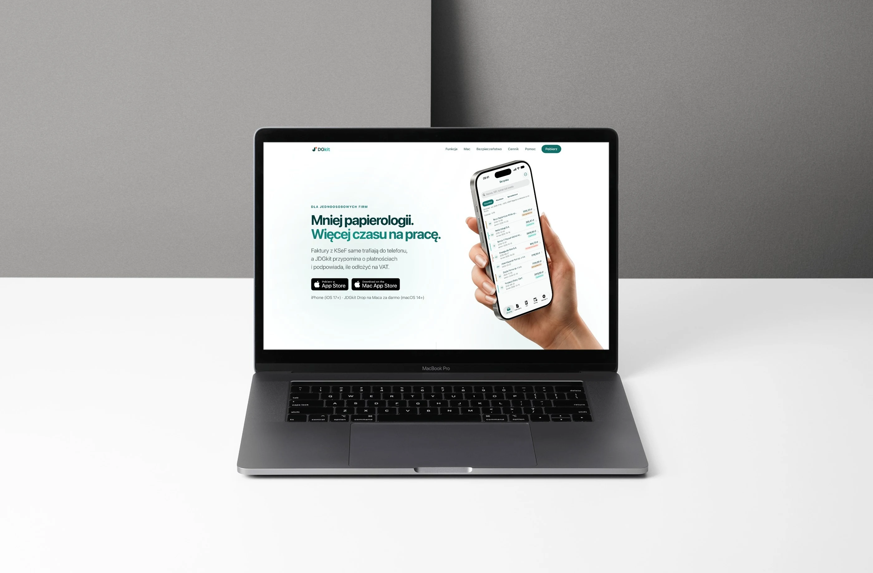 Strona jdgkit.pl na MacBooku — hero „Mniej papierologii. Więcej czasu na pracę” z iPhone'em w dłoni